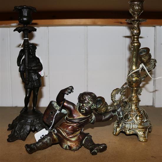 A brass figure of a boy and two candlesticks